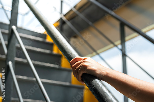 Fotografi A human hand is holding the handrail banister during walking up the stairway at the factory workplace