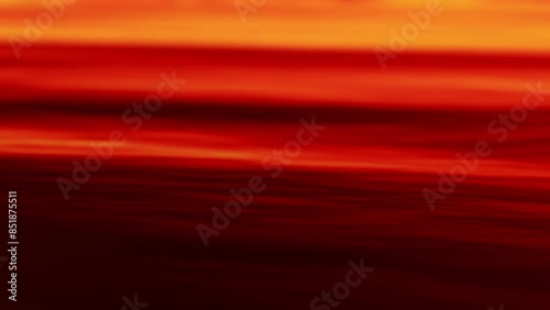 Slow rhythmic motion of water ripple waves flowing by, illuminated with a warm orange red glow from the setting sun at dusk, calm and tranquil minimalist backdrop looped.  