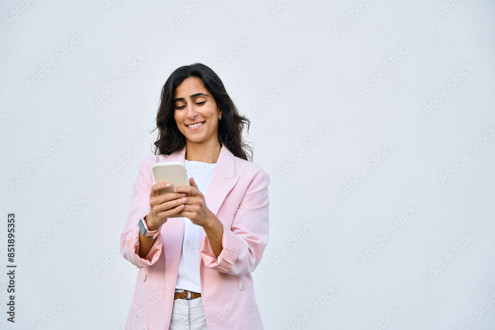 Smiling young middle eastern Israel businesswoman using smartphone mobile phone online app for work isolated on white background. Indian or arabic woman in business suit holding cellphone. Copy space Smiling young middle eastern Israel businesswoman using smartphone mobile phone online app for work isolated on white background. Indian or arabic woman in business suit holding cellphone. Copy space