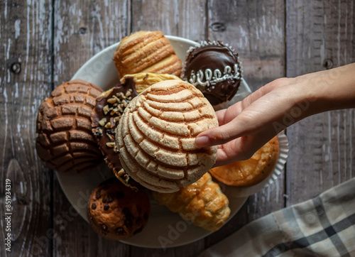 Concept of taking or grabbing food with hands, feminine Mexican hands. Traditional Mexican bakery, sweet bread. holding a CONCHA with left hand baroque chiaroscuro horizontal flat lay image photo