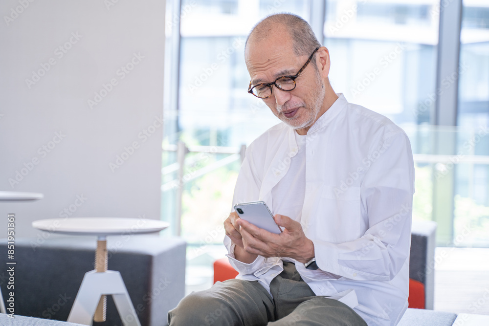 スマートフォンを操作する笑顔のシニア男性 スマートフォンを操作する笑顔のシニア男性