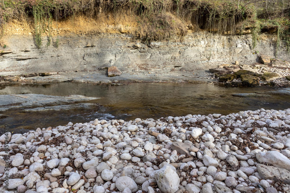 Obraz premium the texture of the riverbank with a stone bed and a leisurely flow, autumn park