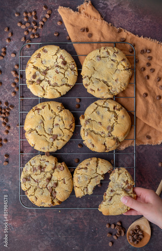 Freshly baked cookies on cooling rack with hand taking cookie