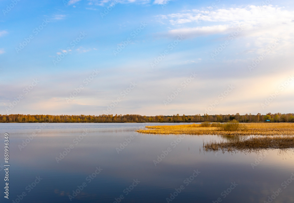A lake with a cloudy sky in the background A lake with a cloudy sky in the background