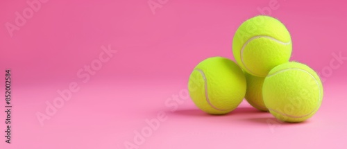Vibrant pink background with an array of tennis balls, capturing a playful and colorful scene with ample negative space, shot in natural light. © Pongsapak