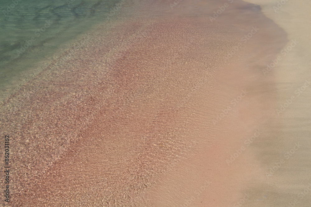 Sandy beach background. Gentle waves crash upon the shore. Pink sand. Pink shells. Elafonisi. Crete. Greece.