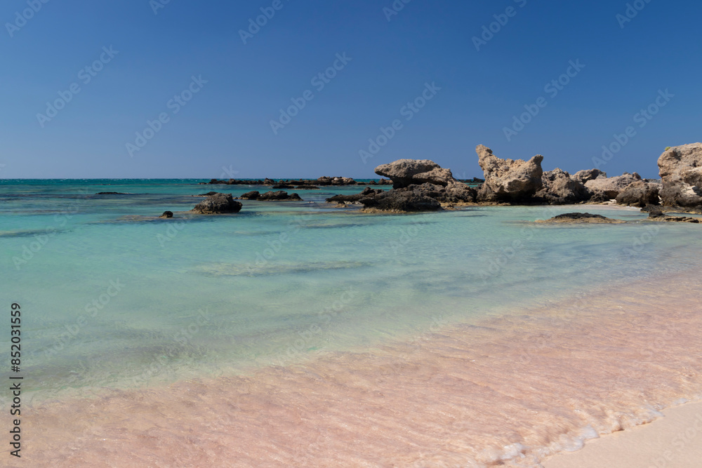 Sandy beach background. Gentle waves crash upon the shore. Pink sand. Pink shells. Elafonisi. Crete. Greece. Sandy beach background. Gentle waves crash upon the shore. Pink sand. Pink shells. Elafonisi. Crete. Greece.