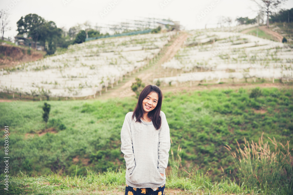 Young asian lady standing and smiling with green backgound outdoor on vacation Young asian lady standing and smiling with green backgound outdoor on vacation