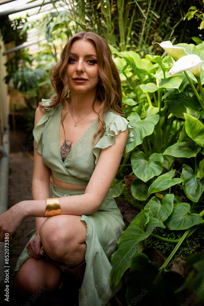 Obraz premium A beautiful young woman is holding a large green leaf. Hot sunny day. Rest on a tropical island. Summer travel girl, active lifestyle