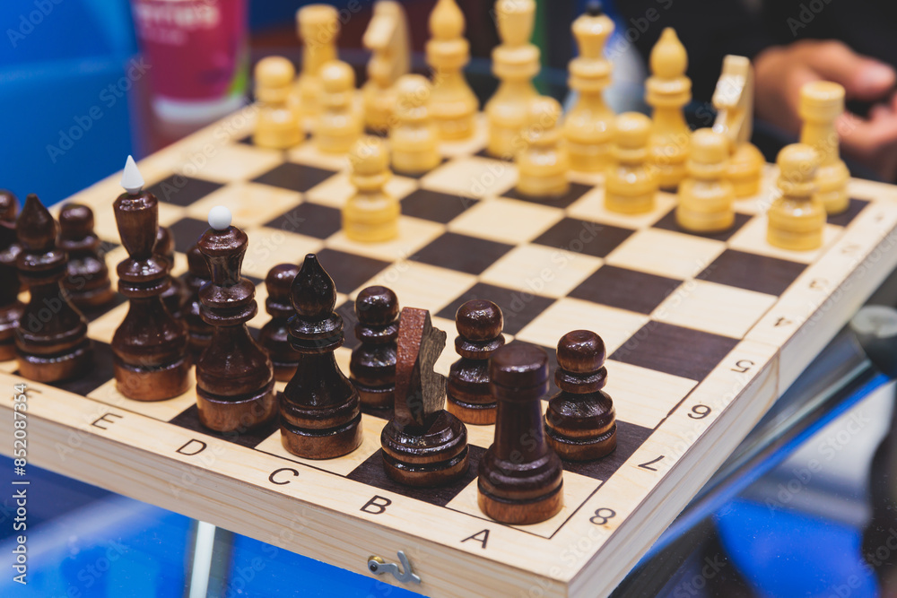 Chess tournament, kids and adults participate in chess match game in indoor hall, players of all ages play, competition in chess school club with chessboards on a table, wooden pieces Chess tournament, kids and adults participate in chess match game in indoor hall, players of all ages play, competition in chess school club with chessboards on a table, wooden pieces