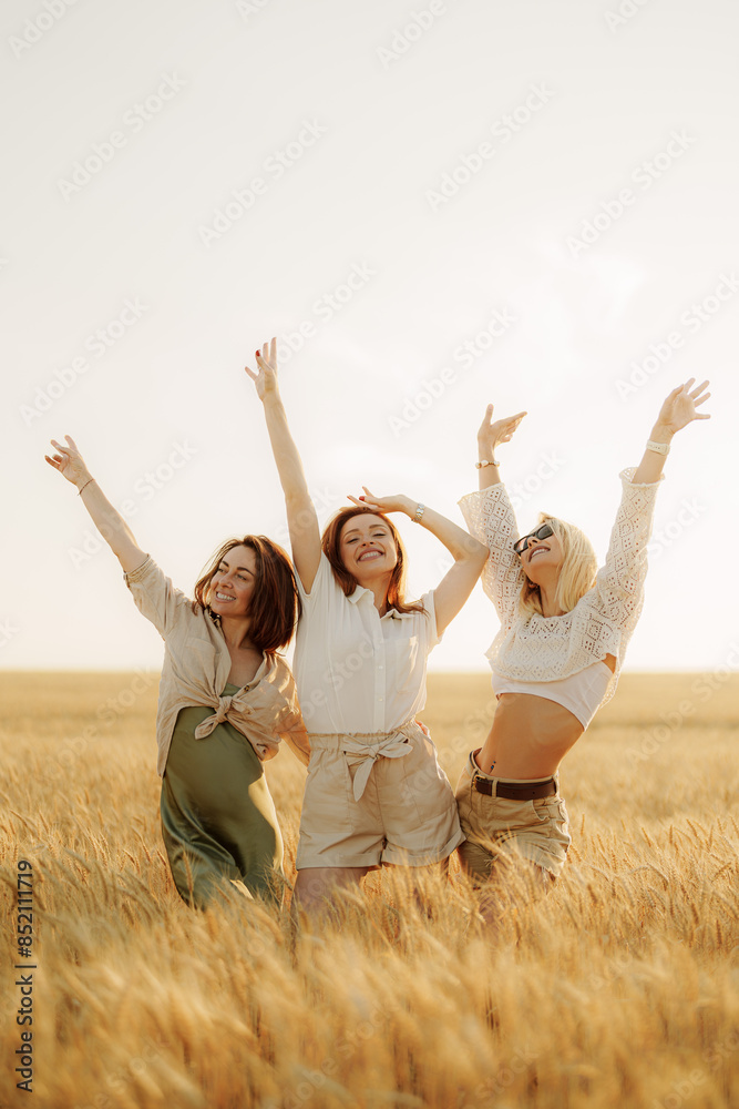 Joyful female friends raising hands in unity in a sunny wheat field. Concept of friendship, freedom, and happiness outdoors. Joyful female friends raising hands in unity in a sunny wheat field. Concept of friendship, freedom, and happiness outdoors.