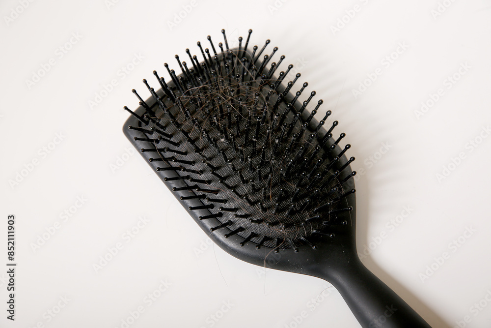Close up of a used dirty hair brush full of hair on white table, hair loss problem concept