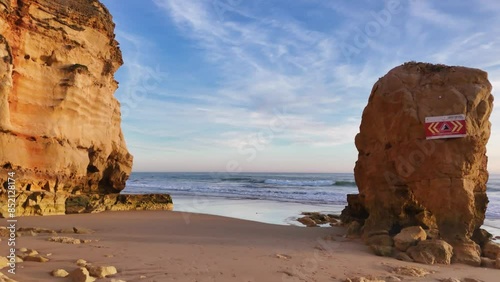 Red-colored rocks and a beautiful beach Praia dos Careanos at sunset, Portugal