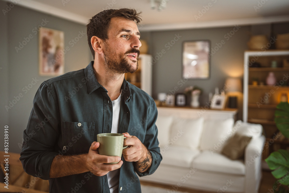 Portrait of adult handsome man drink first coffee in the living room