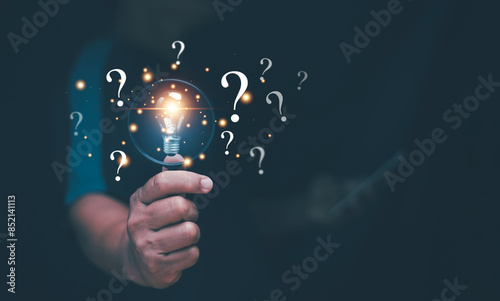 Critical thinking and analysis concept. Businessman holding magnifier glass with glowing lightbulb with question mark icon, New ideas and innovations arise and search for answers. Find solution.