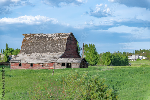 Photography Vintage deteriorating and falling apart barn and a modern house in the backgroun