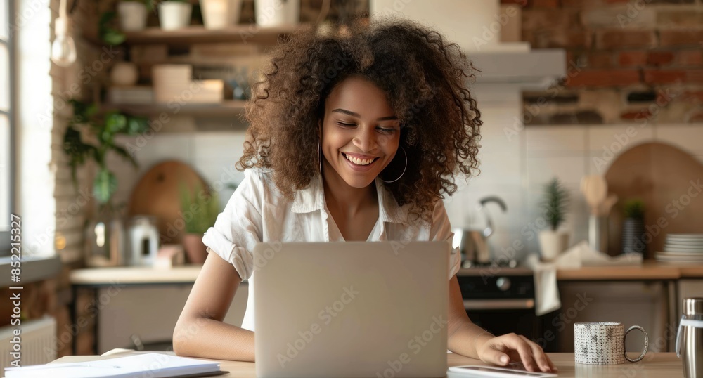 A woman with curly hair is sitting at a table with a laptop in front of her A woman with curly hair is sitting at a table with a laptop in front of her