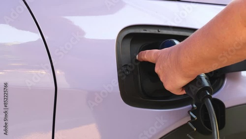 Woman hand pulling out electric charger from car.