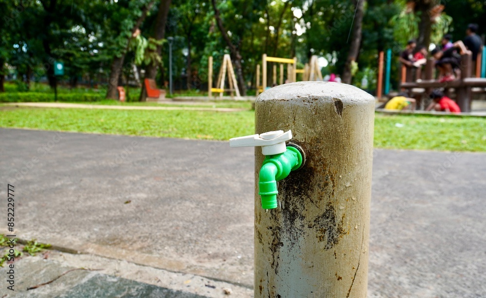 White and green plastic material tap water faucet isolated on horizontal ratio outdoor fresh eco green park and playground environment. White and green plastic material tap water faucet isolated on horizontal ratio outdoor fresh eco green park and playground environment.