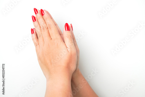 A woman's hand with bright red nail polish forms Hands Pressed Together (Palms Pressed Together) gesture as a sign of praying. Isolated on white background.