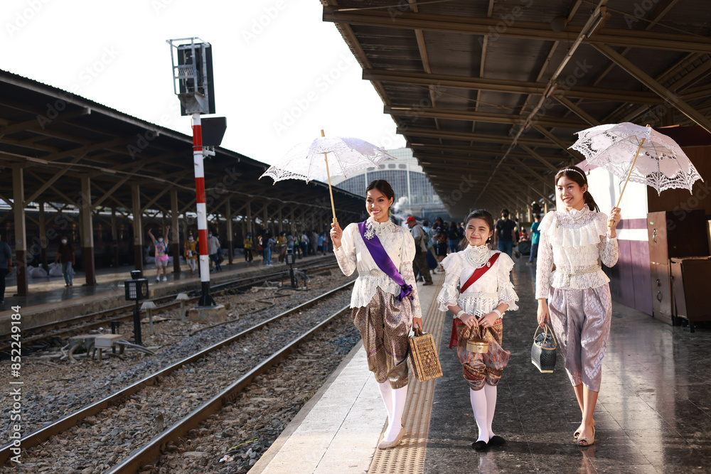 Three sisters  in traditional Thai costumes having their photo taken at the train station for the retro train event in Thailand 