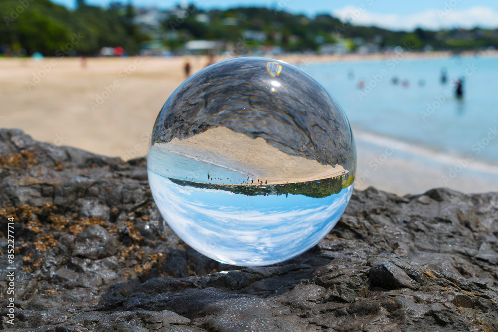 Glass Ball on the Rock, at the background is Panoramic View of Maraetai Beach Auckland, New Zealand; White Sandy Beach during Low Tide