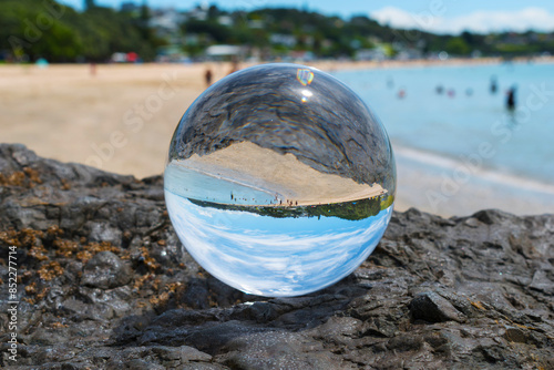 Obraz na płótnie Glass Ball on the Rock, at the background is Panoramic View of Maraetai Beach Auckland, New Zealand; White Sandy Beach during Low Tide w salonie