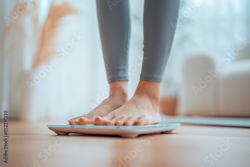 Closeup of feet, Young Asian woman standing on scales to measure her weight at home, Checking result of her slimming diet. Healthy living concept