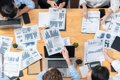 Panorama top view diverse group of business analyst team analyzing financial data report paper on meeting table. Chart and graph dashboard by business intelligence analysis. Meticulous