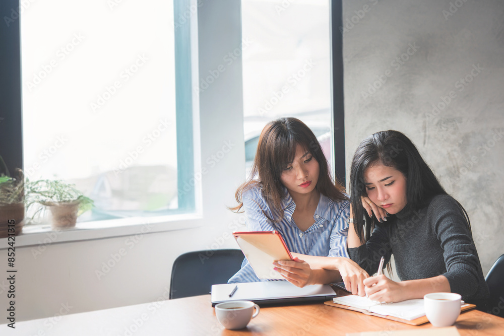 Two Young Asian woman learning and reading a book together at coffee shop or cafe in the morning, vintage tone Two Young Asian woman learning and reading a book together at coffee shop or cafe in the morning, vintage tone