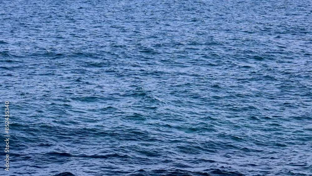 This is a close-up of sea waves in the middle of the sea on a sunny day. Real time