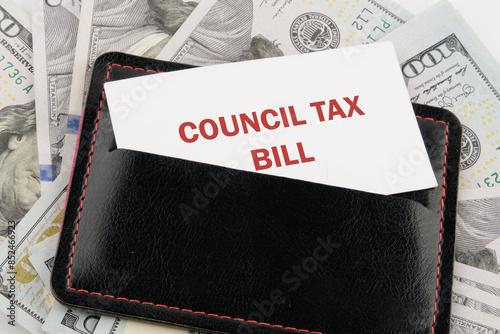 Business and finance concept. COUNCIL TAX BILL text written on a business card in a black leather accessory against the background of American dollars photo