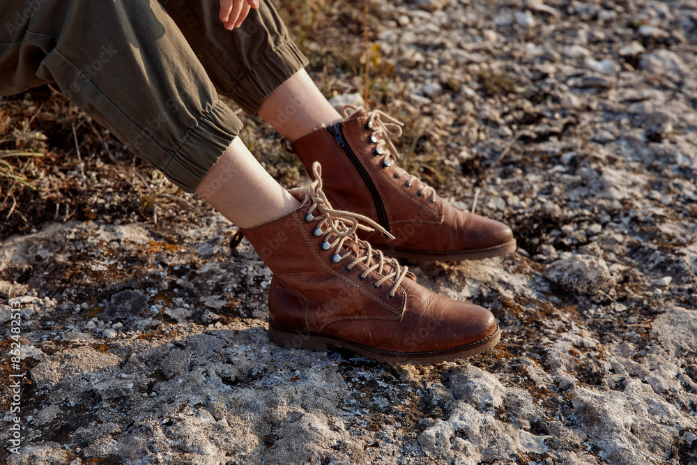 Woman in brown boots sitting on rocky surface enjoying outdoor adventure experience Woman in brown boots sitting on rocky surface enjoying outdoor adventure experience