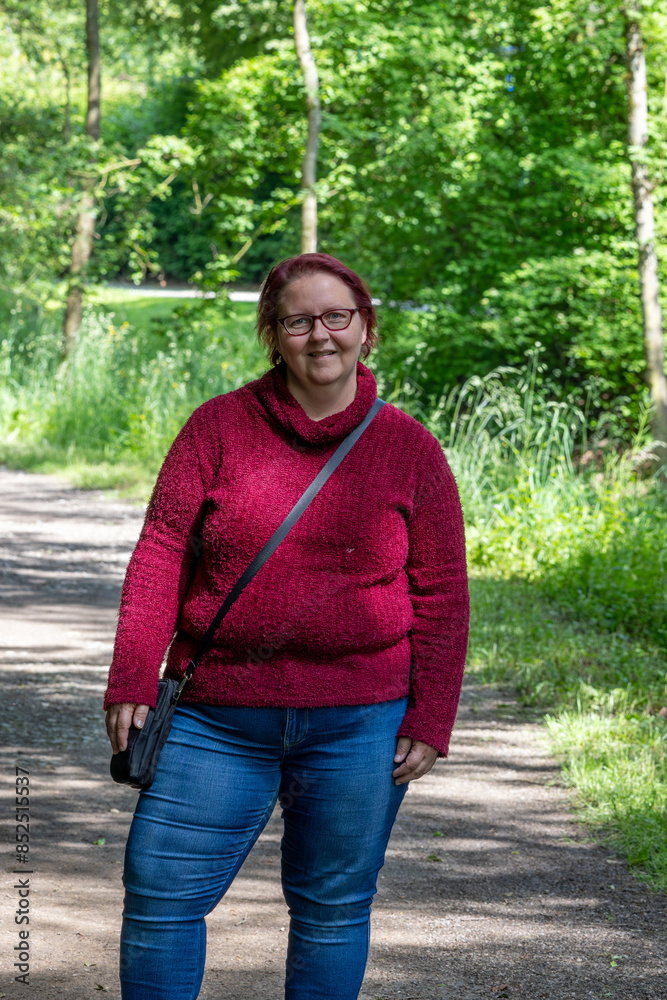 Portrait of a red-haired cheerful woman in the forest on a beautiful sunny summer day Portrait of a red-haired cheerful woman in the forest on a beautiful sunny summer day