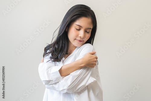 Photos Smiling positive, hugging oneself happy asian young woman hands hug herself shoulders enjoy joyful, self hugging, self love and self care, face expression self esteem standing isolated on background