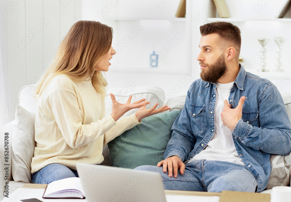 A man and woman are seated on a couch engaged in conversation.