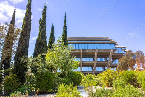 A scenic view of the iconic Geisel Library at UC San Diego, surrounded by lush greenery and tall cypress trees.