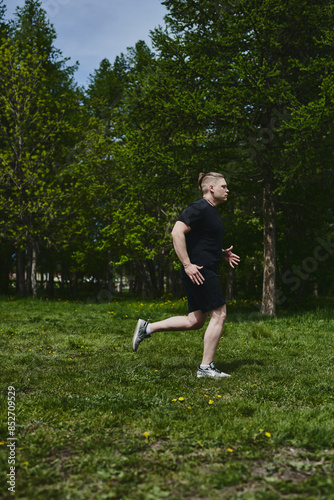 Caucasian male athlete jogging outdoors in a summer park