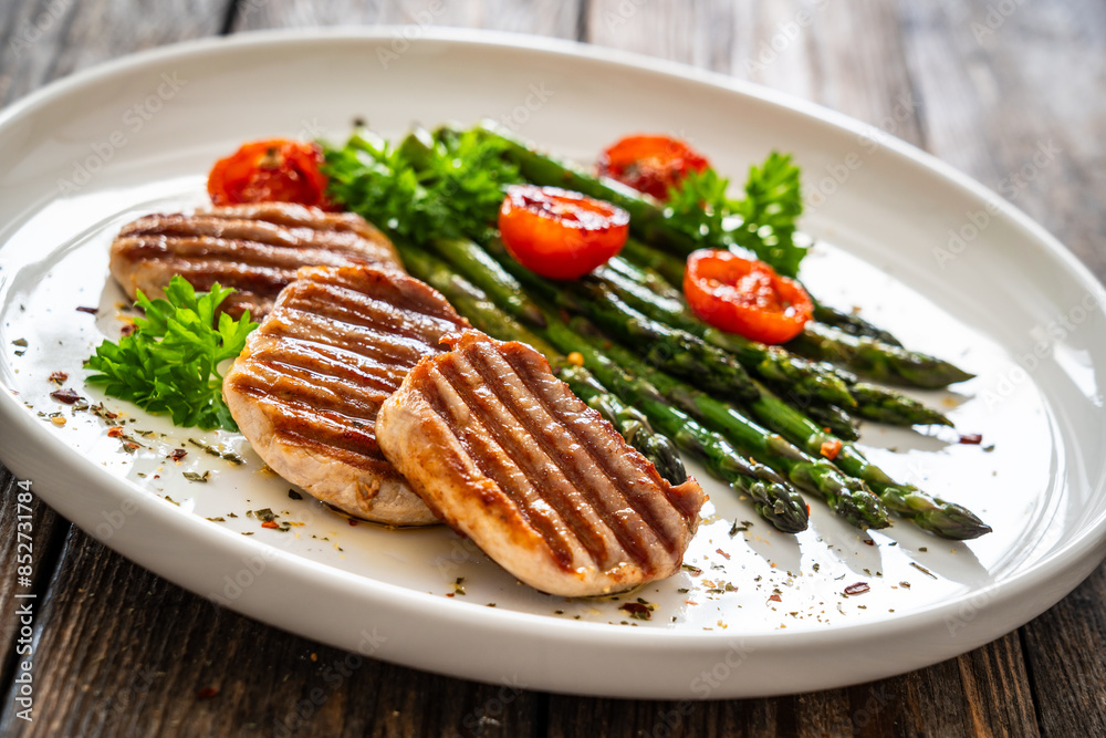 Pork loin steaks and cooked green asparagus on wooden table
Pork loin steaks and cooked green asparagus on wooden table