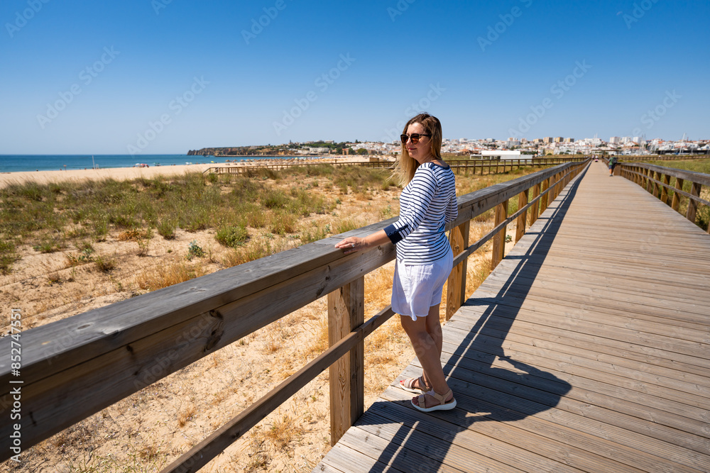 Beautiful woman walking on seaside promenade - Portugal, Algarve, Lagos
