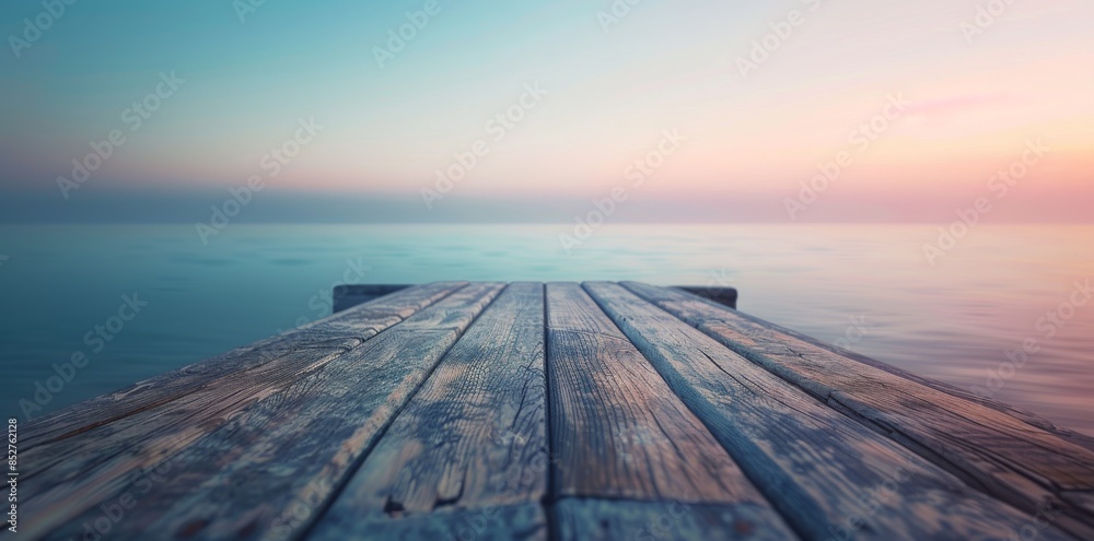 Obraz premium Wooden dock extending into tranquil sea under pastel sunset sky.