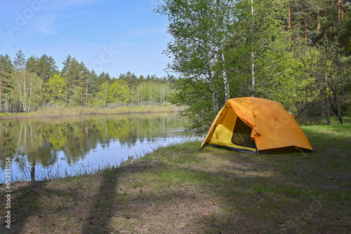 Yellow tent on the bank of a forest river.