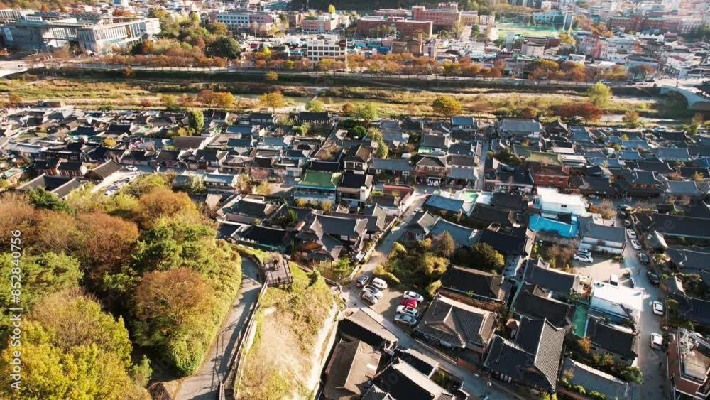 aerial view of Jeonju Hanok Village in Korea, showcasing a dense cluster of traditional Korean houses with distinct dark tiled roofs and stone walls, contrasted by surrounding modern buildings. aerial view of Jeonju Hanok Village in Korea, showcasing a dense cluster of traditional Korean houses with distinct dark tiled roofs and stone walls, contrasted by surrounding modern buildings.