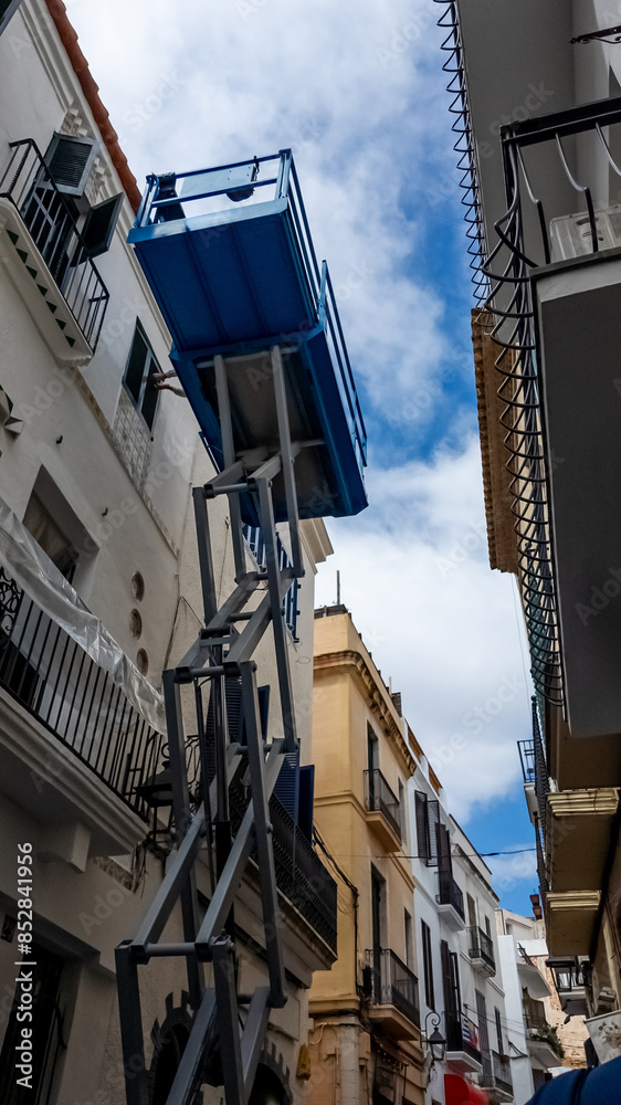 Narrow alley view with unique blue balcony in Mediterranean architectural style under a cloudy sky, suitable for travel and cultural themes Narrow alley view with unique blue balcony in Mediterranean architectural style under a cloudy sky, suitable for travel and cultural themes