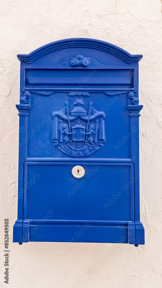Bright blue traditional postal mailbox mounted on a white wall, ideal for communication, postal services, and National Postal Worker Day concepts Bright blue traditional postal mailbox mounted on a white wall, ideal for communication, postal services, and National Postal Worker Day concepts