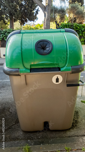 Green and tan residential compost bin on a sidewalk, promoting recycling and environmental conservation, suitable for waste management and eco-friendly practices content