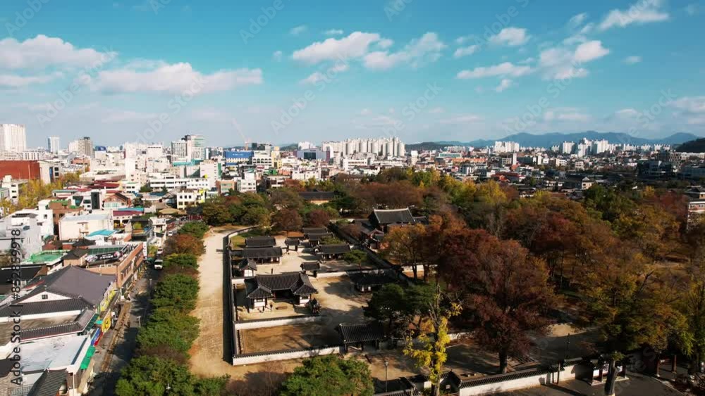 aerial view of Jeonju Hanok Village in Korea, showcasing a dense cluster of traditional Korean houses with distinct dark tiled roofs and stone walls, contrasted by surrounding modern buildings. aerial view of Jeonju Hanok Village in Korea, showcasing a dense cluster of traditional Korean houses with distinct dark tiled roofs and stone walls, contrasted by surrounding modern buildings.