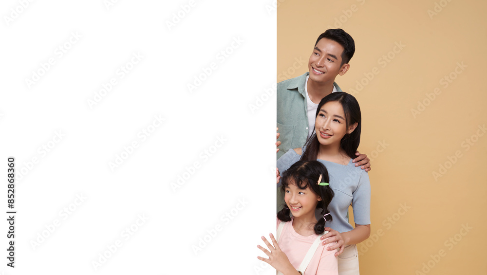 portrait Happy asian family with empty banner for advertising isolated on nude color background. portrait Happy asian family with empty banner for advertising isolated on nude color background.