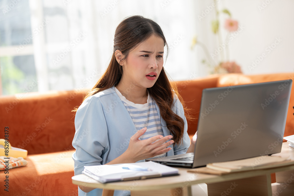 Asian Frustrated Woman Working on Laptop with Documents at Home Asian Frustrated Woman Working on Laptop with Documents at Home