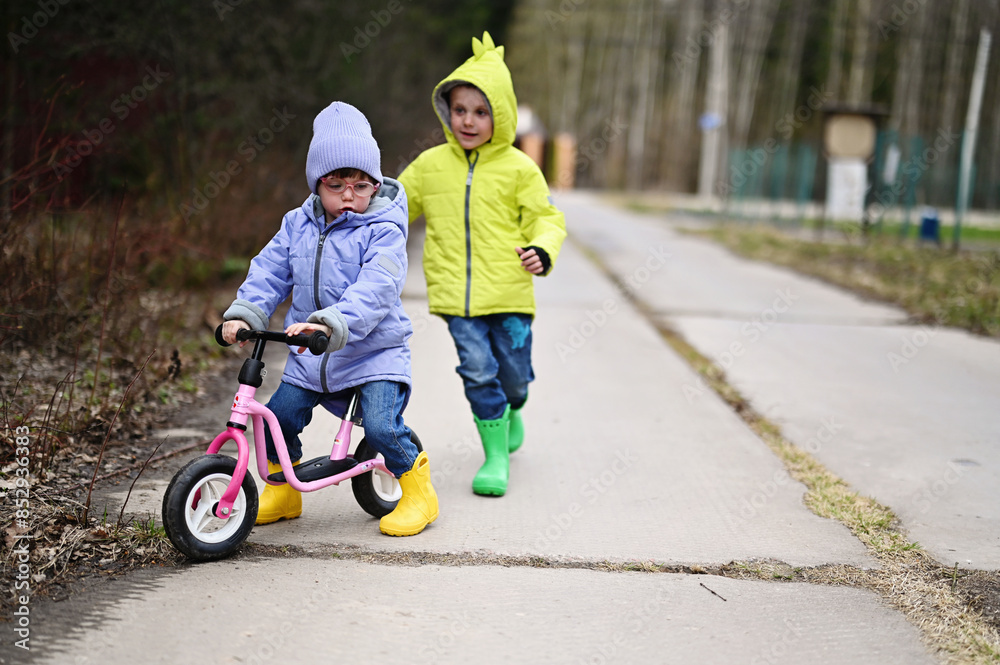 Toddler girl on balance bike with her brother Toddler girl on balance bike with her brother